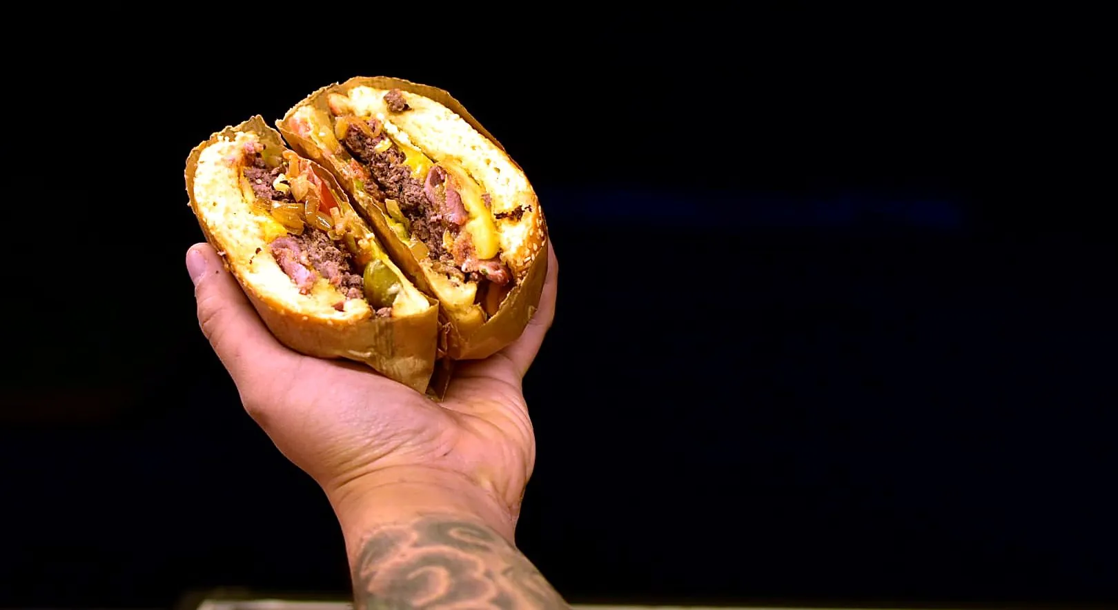Burger maison coupé en deux, tenu à la main